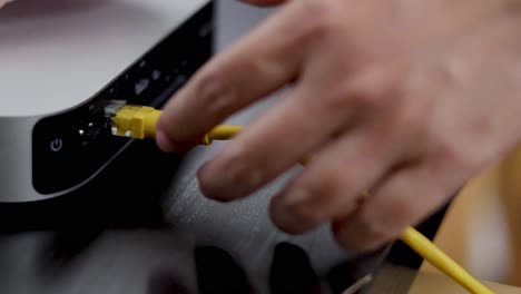 hands plugging in a yellow cable to a device