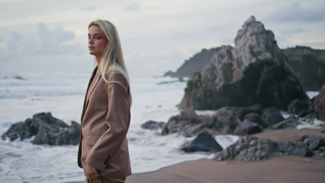 Calm girl contemplating ocean waves in evening. Attractive model turning camera