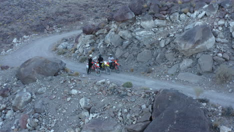 Three-motocross-bikers-standing-in-row-on-gravel-road