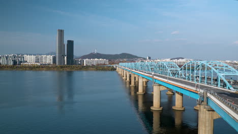 aerial time lapse of cars traffic driving on dongjak bridge crossing over han river, distant view of n seoul tower in skyline, south korea