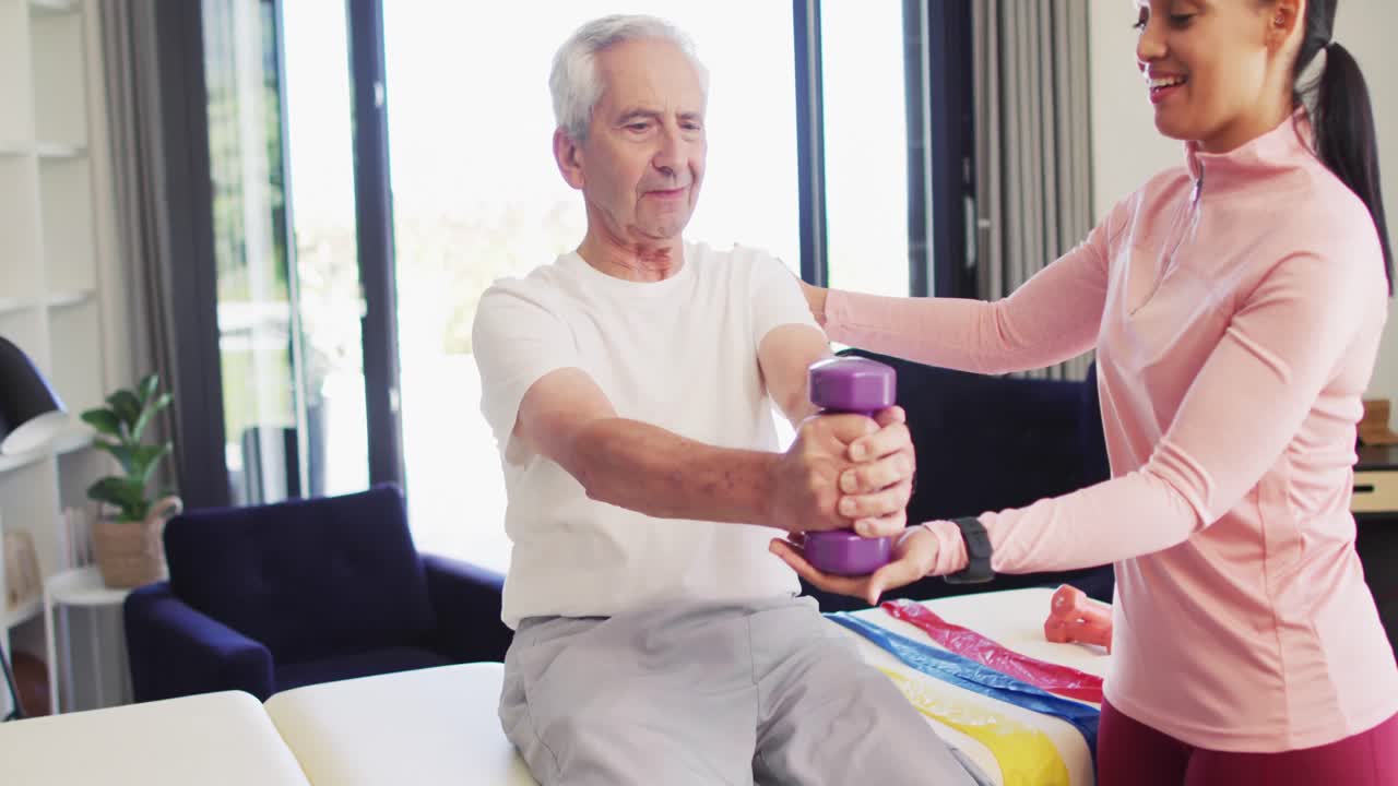 행복한 두 인종 여성 물리 치료사가 백인 노인과 함께 운동하는 비디오