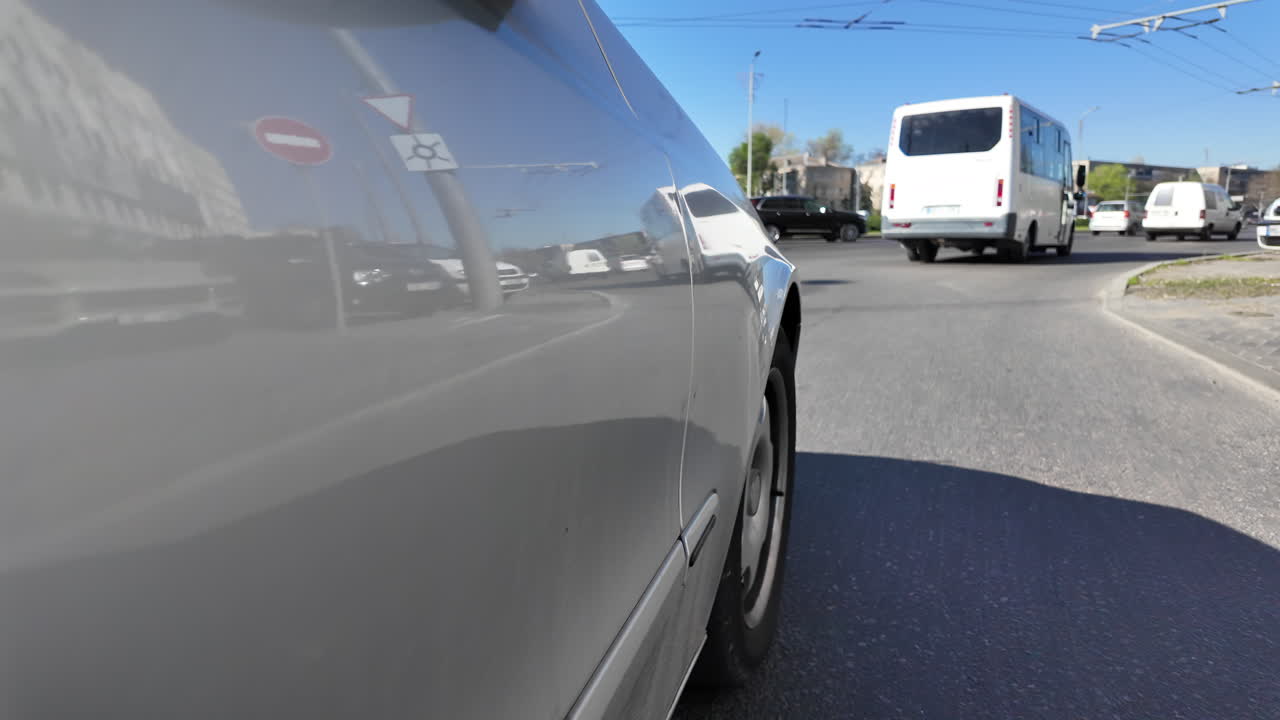 Close up of a silver car side driving down the road in city traffic