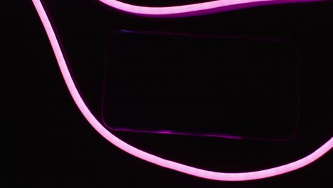 Komposition-Eines-Smartphones-Mit-Rosa-Neonlichtern-Auf-Schwarzem-Hintergrund