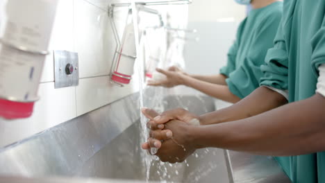 Midsection-of-diverse-female-and-male-surgeons-washing-hands-thoroughly,-slow-motion