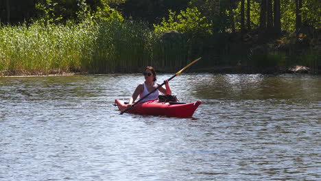 mujer en kayak remando en naturaleza tranquila en el norte, cámara lenta