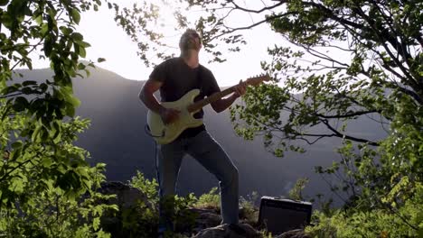 guitar player in nature behind a drop