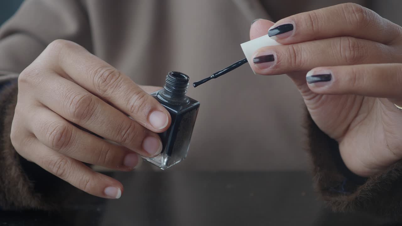 Close-Up of Woman's Hands Opening Black Nail Polish Bottle