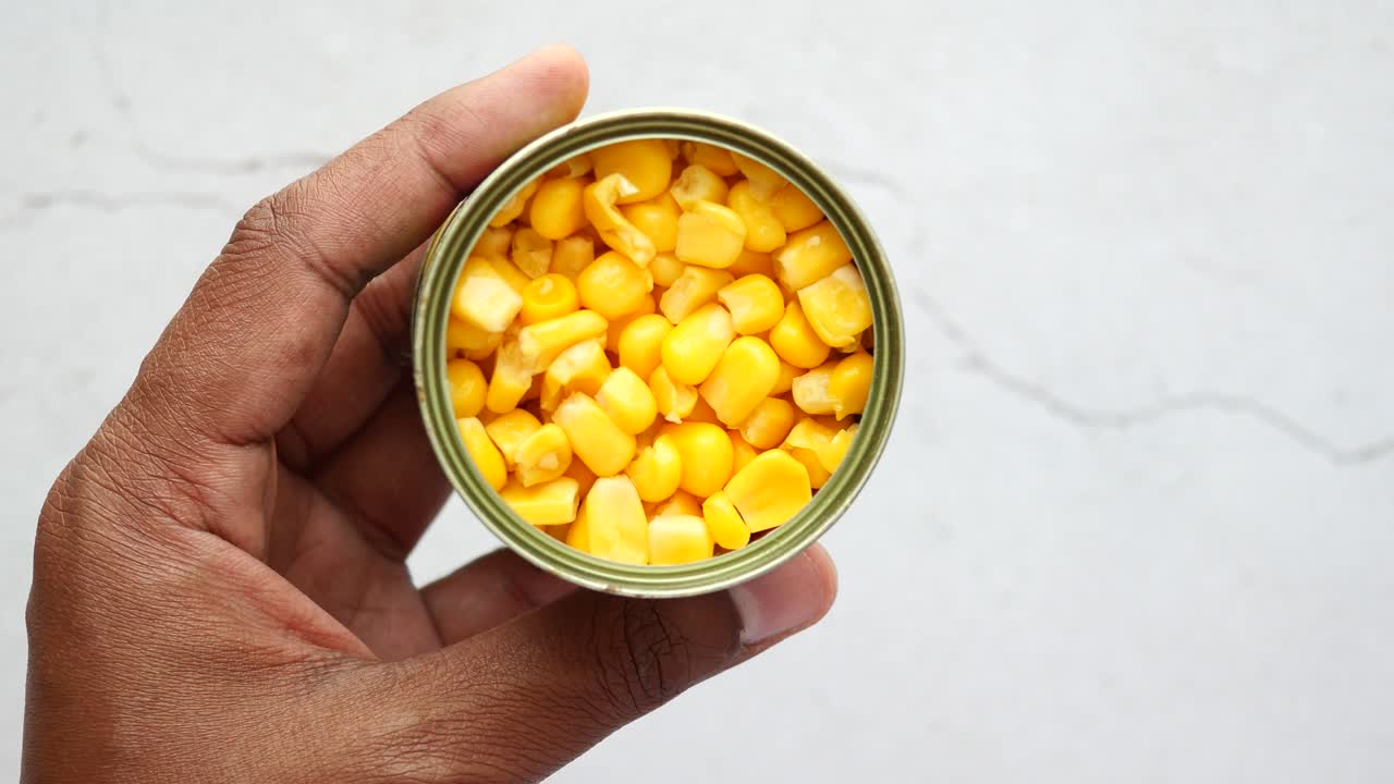 maíz enlatado en la mano y la cuchara