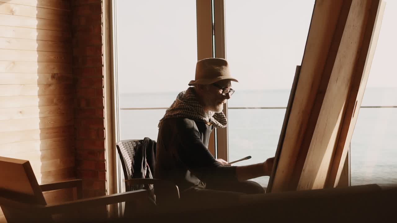 artista senior pintando junto al mar