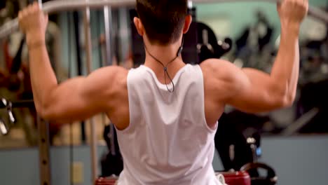 rear extreme closeup of young bodybuilder doing lat pulldowns on a machine