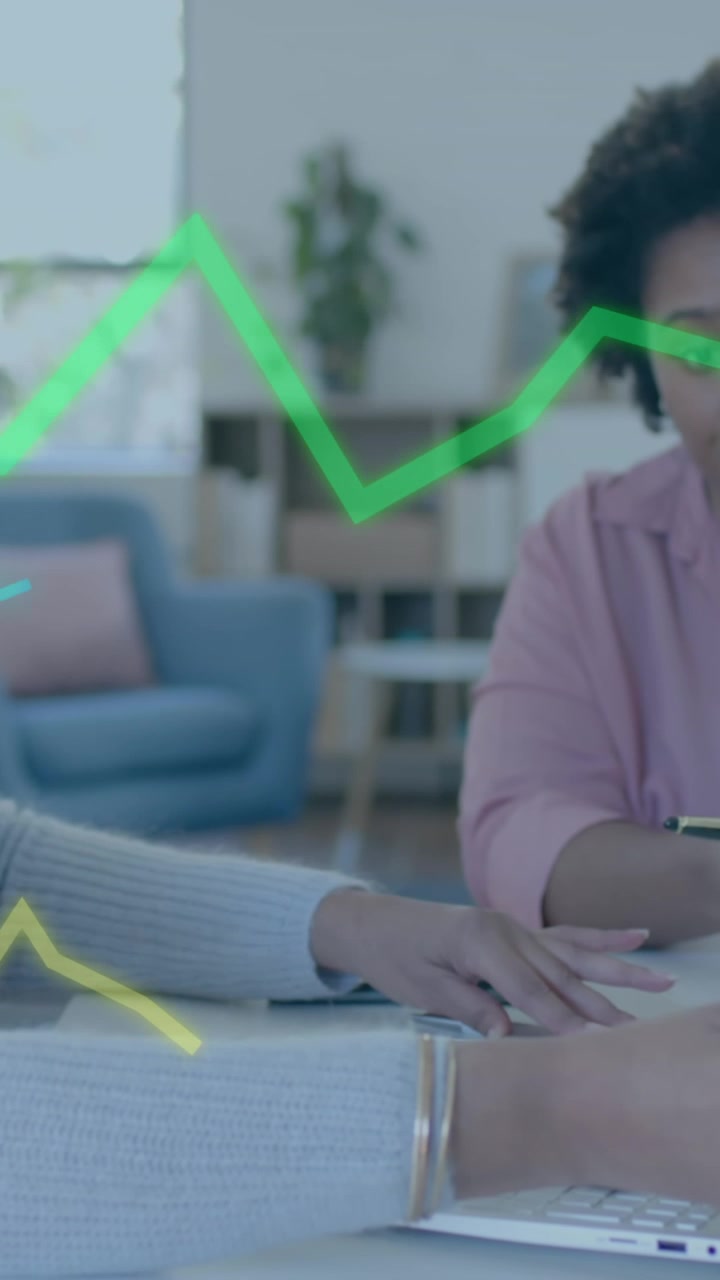 Elaborazione dati grafici su diverse colleghe con laptop e tablet che discutono alla scrivania.