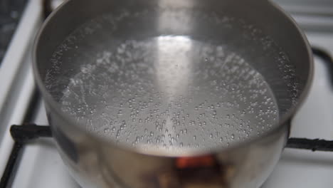 close up of water bubbles starting to form before boiling in a stainless steel pot on the fire stove