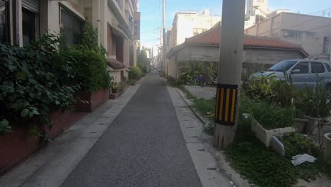 pov walking down a residential street alley past houses and apartment buildings. ishigaki, okinawa, japan. circa september 2019