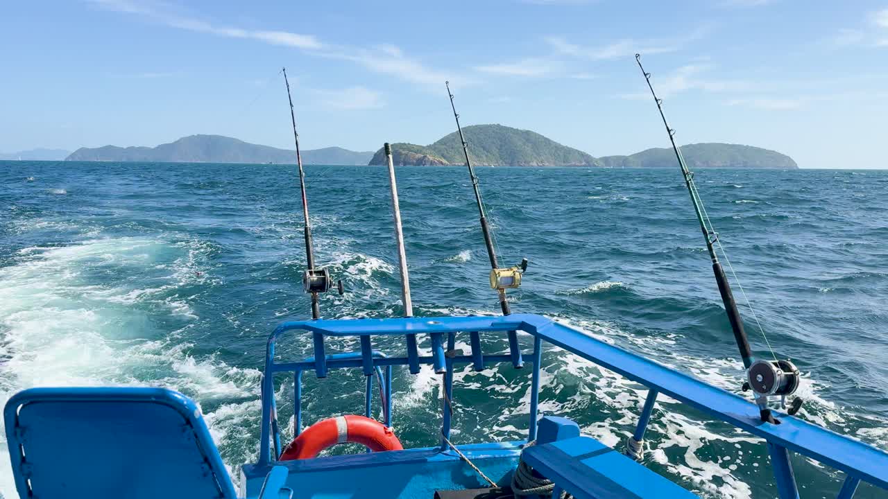 Un peschereccio a strascico naviga su onde oceaniche agitate vicino a Ko Racha Yai, sotto cieli sereni a Phuket, Thailandia.