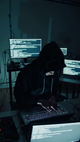 a dramatic, low-angle shot of a hooded figure typing on a laptop, surrounded by glowing screens
