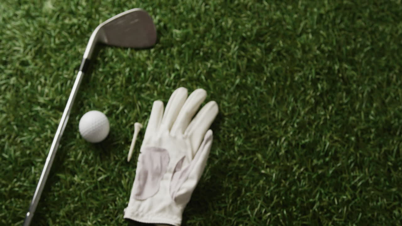 Close-up de taco de golfe, bola e luva na grama, espaço para texto, em câmera lenta