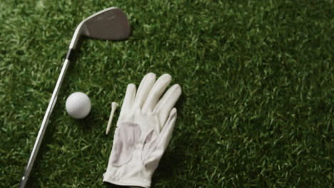close up of golf club, ball and glove on grass, copy space, slow motion
