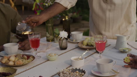 friends enjoying tea and snacks at an outdoor evening gathering