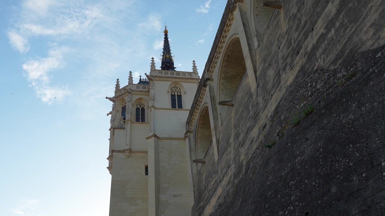 Video al rallentatore della torre della cappella e delle mura esterne in pietra del Castello Reale di Amboise, con uccelli che volano sopra durante l'ora d'oro nella Valle della Loira, Francia.
