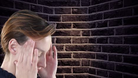 vista de cerca de una mujer caucásica estresada que sostiene su cabeza contra la pared de ladrillo en el fondo
