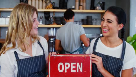 Portrait-of-two-waitresses-are-smiling-and-holding-open-sign