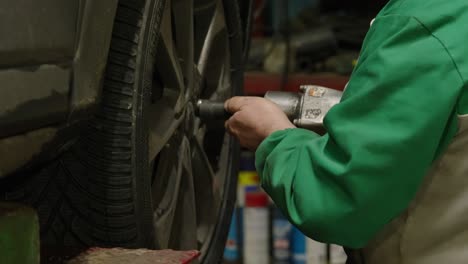 close-up of mechanic's hands screwing a wheel with an automatic screwdriver