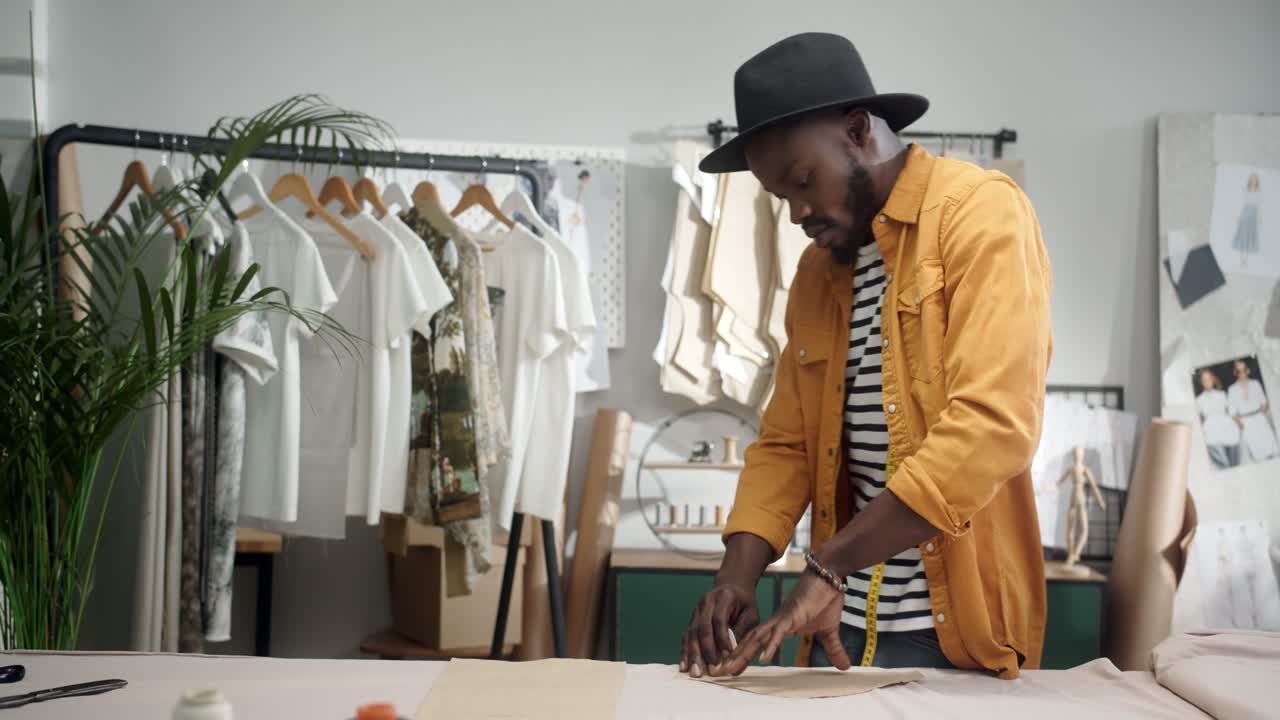 Glad ung designer tegner en skitse på stoffet og danser i studiet.