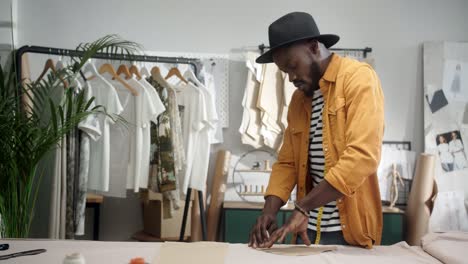 cheerful young designer drawing an outline on the cloth and dancing in studio