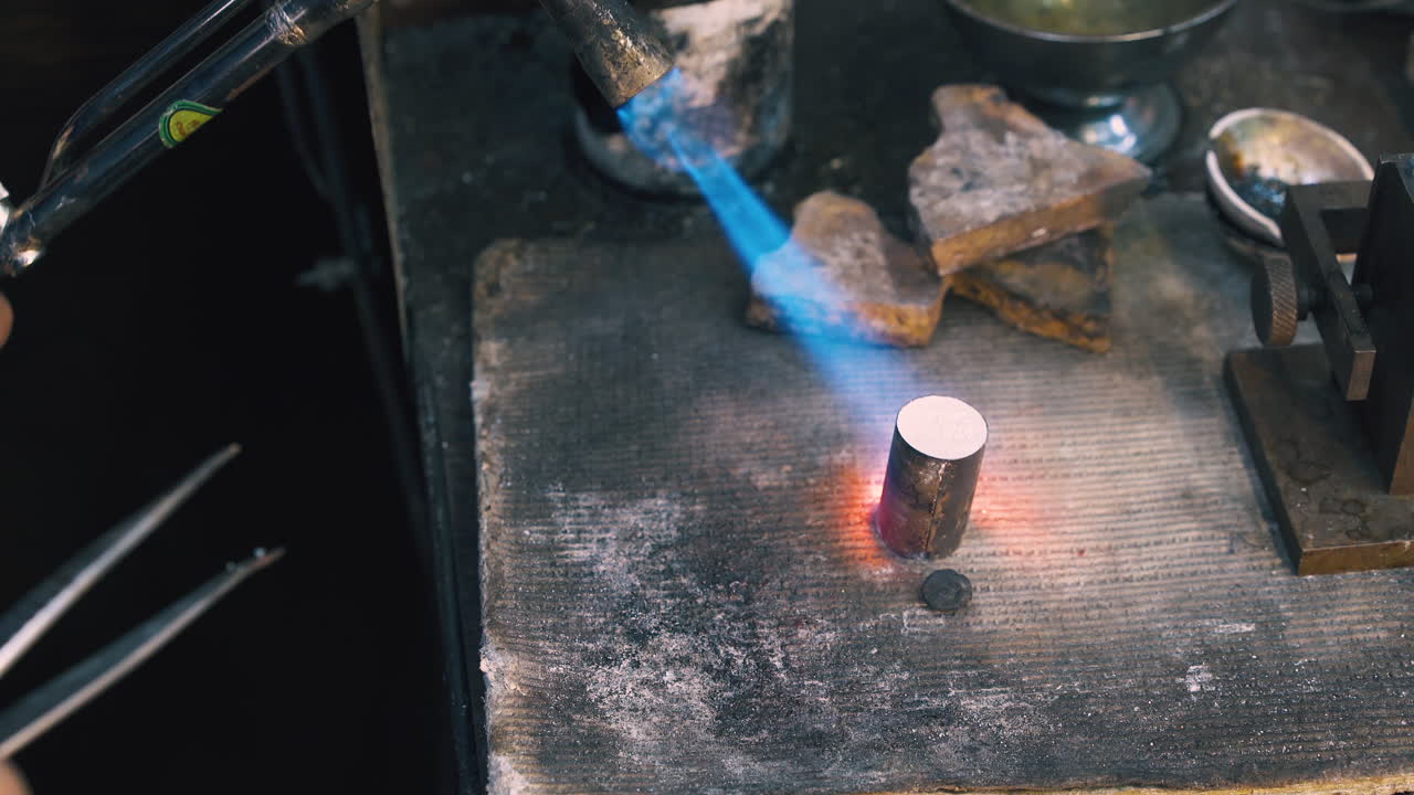 worker heats metal bar to make detail in workshop closeup