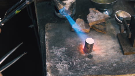 worker heats metal bar to make detail in workshop closeup