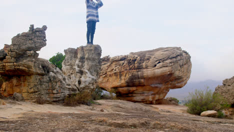 man sitting on rock looking through binoculars 4k