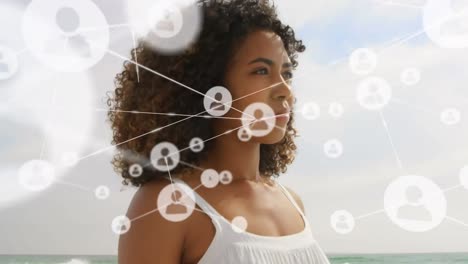 Animation-of-network-of-connections-with-people-icons-over-woman-in-beach