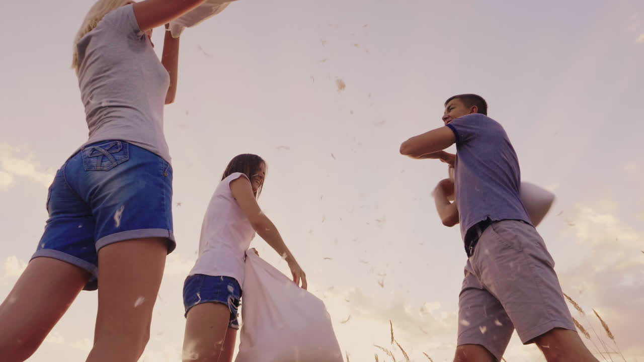 pelea de almohadas un grupo de amigos se divierten - se golpean con almohadas plumas vuelan a cámara lenta vi