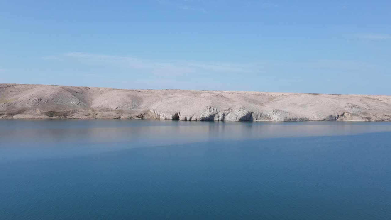 크로아티아의 배경에 하얀 돌로 된 섬 페이지가 있는 고요한 푸른 아침 아드리아 해 위로 이륙