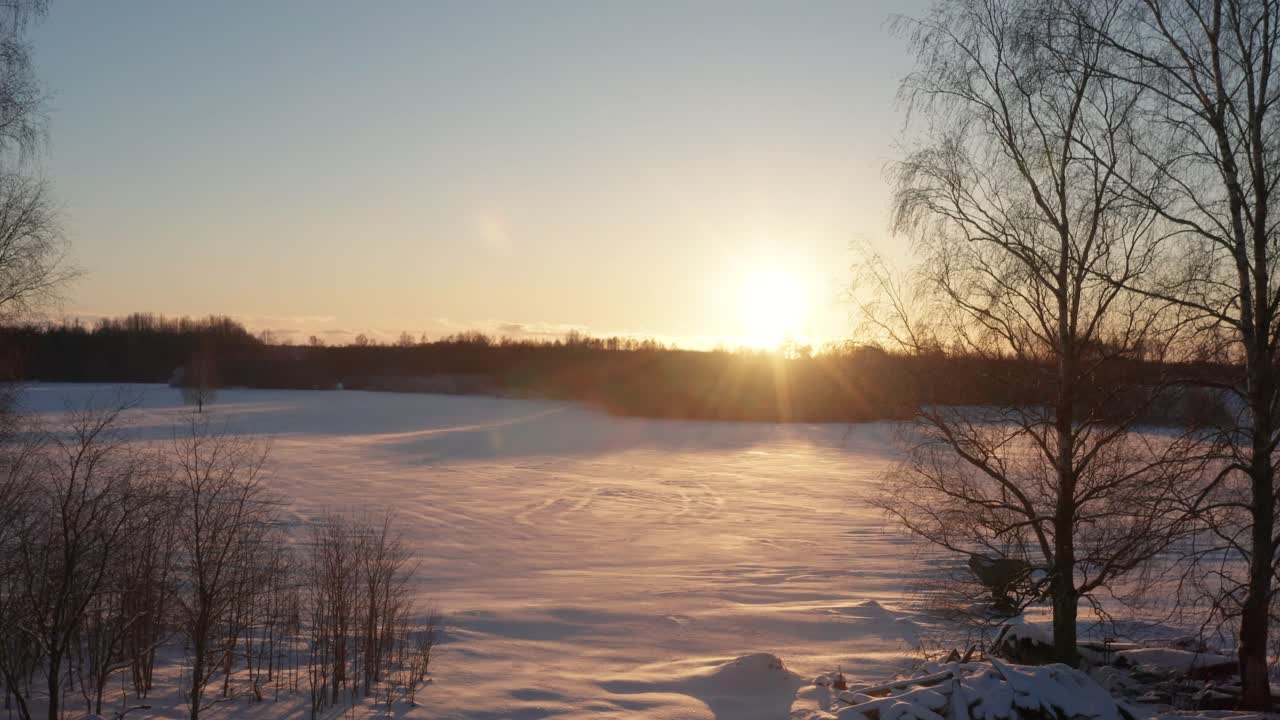 숲 위 에 밝은 겨울 해가 지는 동안 밝은 눈 인 농경지 가 드러납니다.