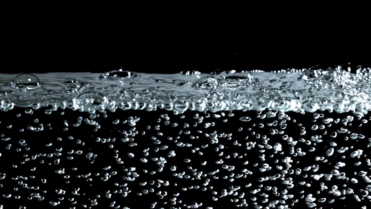 Nombreuses petites bulles s'élevant dans de l'eau claire sur fond noir