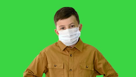 boy wearing protective face mask looking at camera on a green screen, chroma key