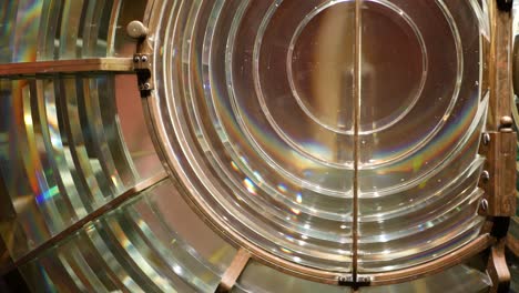 fresnel lens with brass structure, nautical lighthouse tower. detail of the glass lantern with rainbow spectrum. system of lamps and lenses to serve as a navigational aid. old sea searchlight beacon.