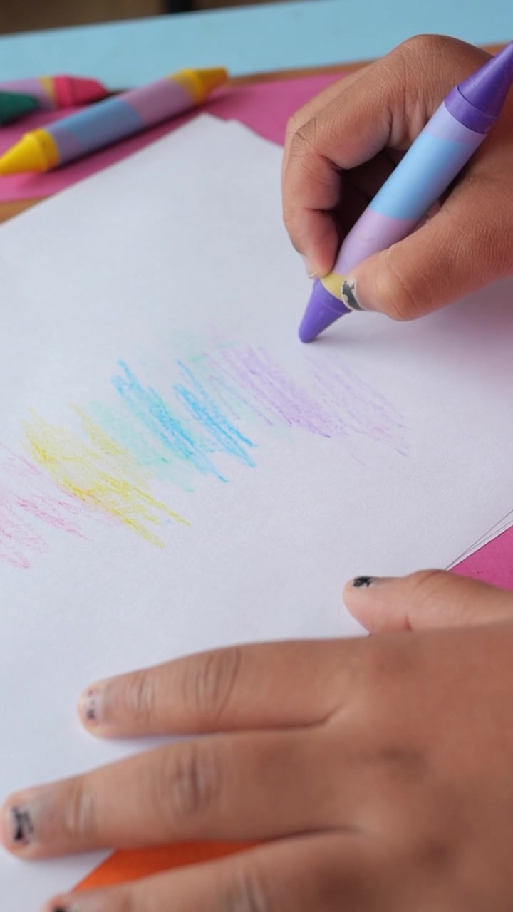 Close-up da Mão de uma Criança Desenhando com um Giz de Cera Roxo