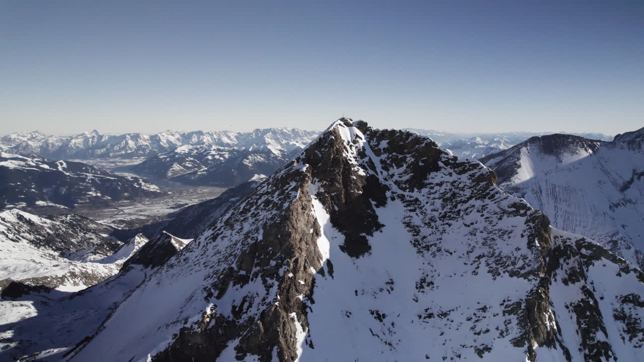 Drone Flight around Majestic Snow-Capped Mountain Peak with Crisp Blue Sky Background - Sunny Day Aerial Panorama