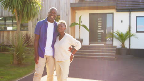 portrait of senior couple standing in driveway in front of dream home together