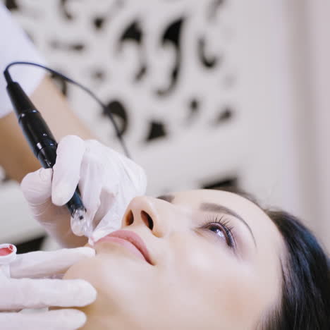 a professional tattoo artist makes lip makeup for the client in the beauty salon. close-up. blurred background.