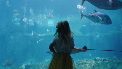 little girl in aquarium looking at stingray swimming in tank curious child watching marine animals in oceanarium having fun learning about sea life in aquatic habitat