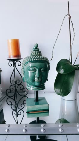 teal green buddha head decor with orchid plant