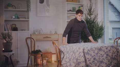 young man setting tablecloth on table