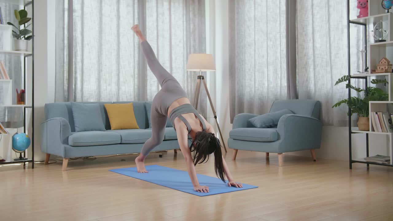 家でマットの上で様々なアサナを練習しているスポーツ服を着た若いアジアのアスレチックな女性