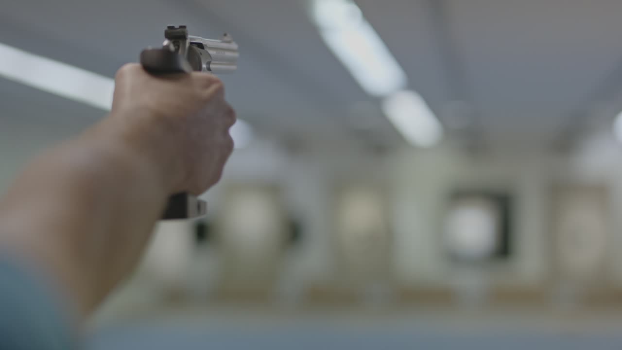 el revólver está apuntando al campo de tiro y disparando.