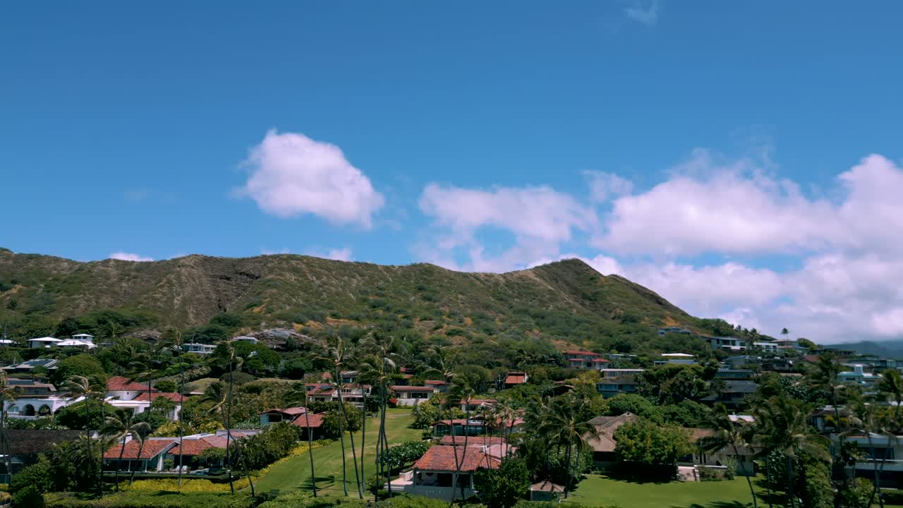 vista aérea estática de la cabeza de diamante detrás de las casas en kahala oahu hawai mientras las nubes pasan sobre el cielo azul