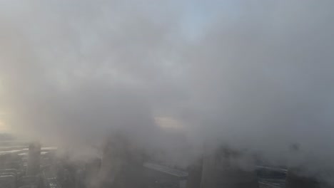 aerial view of uk power station cooling towers overlooking smoke steam emissions at sunrise