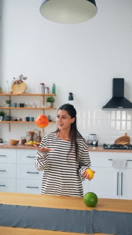 mujer haciendo malabarismos con frutas en la cocina